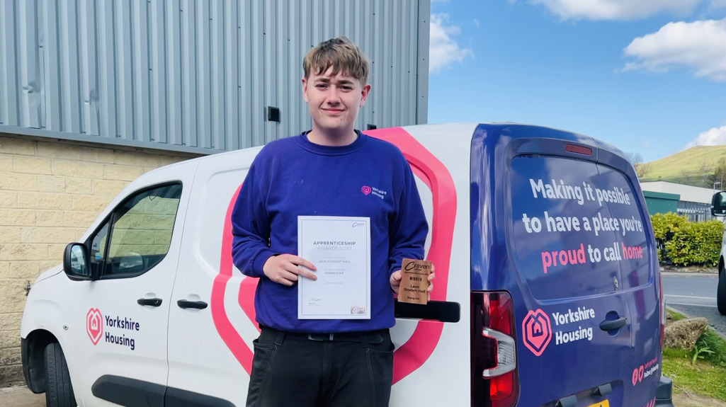 Our award winning apprentice Leon standing with his certificate in front of a Yorkshire Housing van