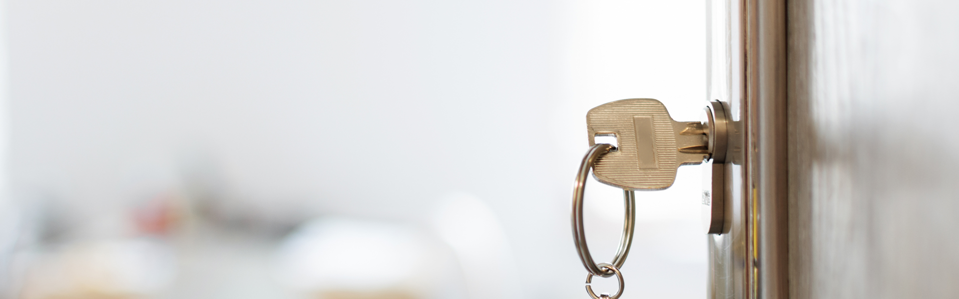 Front door open into a home with the key and house keyring dangling from the lock.