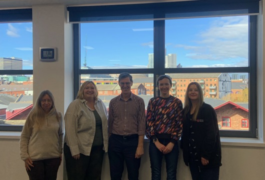 Five of our tenancy coaches standing together and smiling in front of a window 