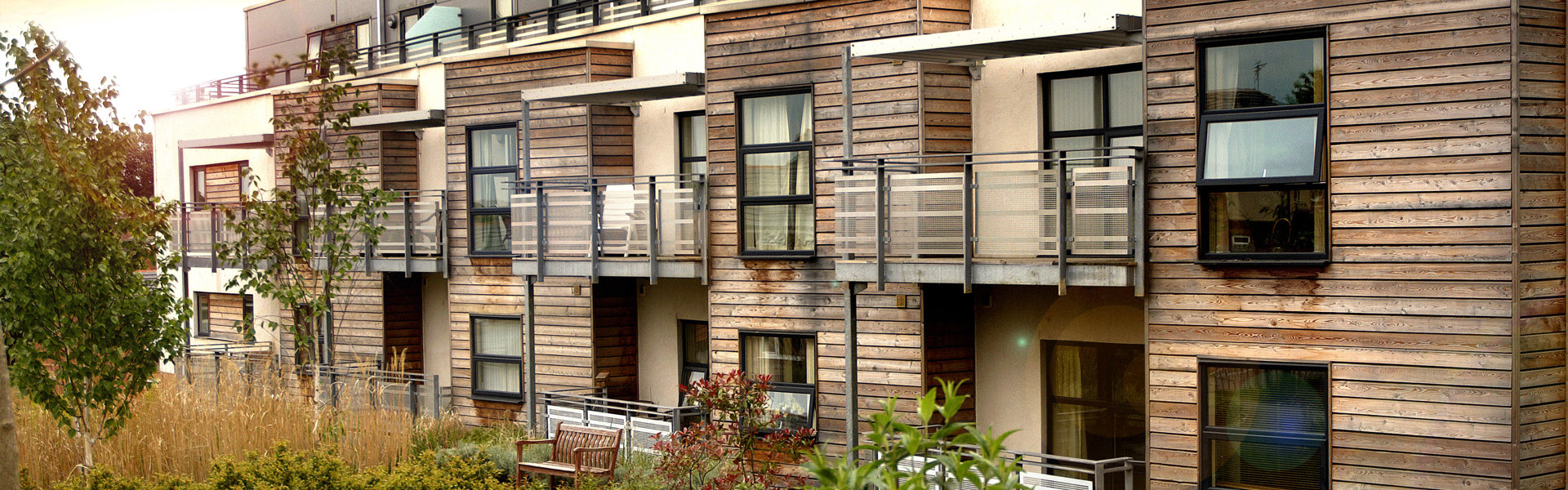 Modern flats with wood panel frontage and balconies overlooking gardens