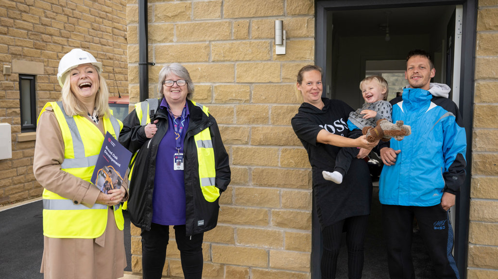 Tracy Brabin with a Yorkshire Housing colleague stood on a doorstep laughing with a young family