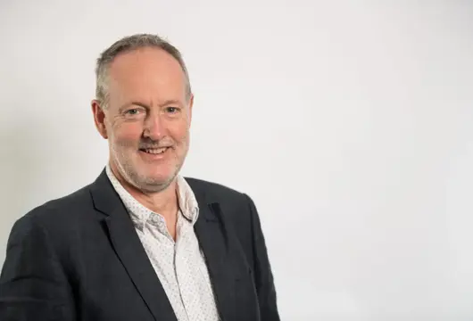 A photograph of Matthew Harrison - Chair of South Yorkshire Housing Partnership. He is wearing a suit with a dark grey jacket and a white polka dot shirt.