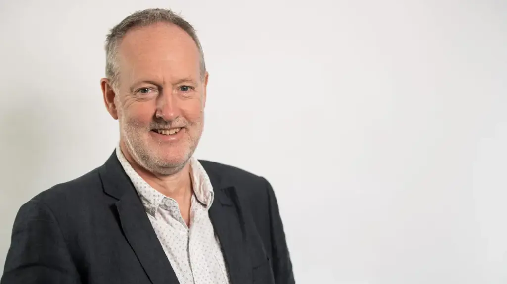 A photograph of Matthew Harrison - Chair of South Yorkshire Housing Partnership. He is wearing a suit with a dark grey jacket and a white polka dot shirt.