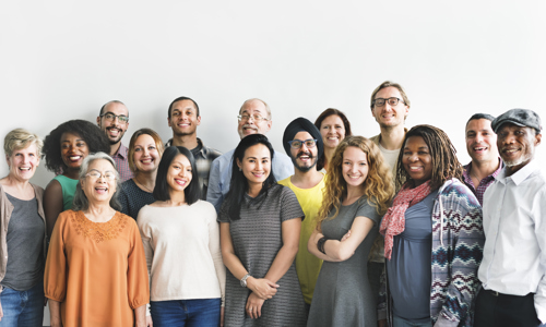 A big group of people wearing a variety of colours smiling at the camera