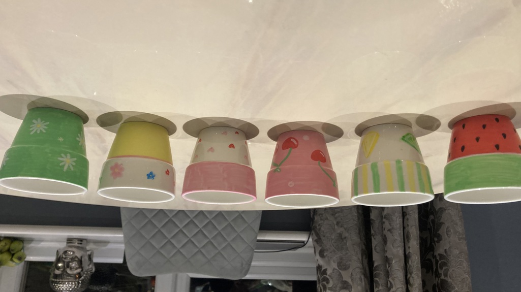 Hand-painted pots lined up on a dining table