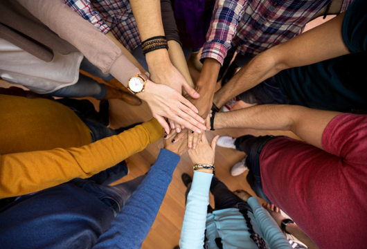 Eight hands all together in the middle to represent a team