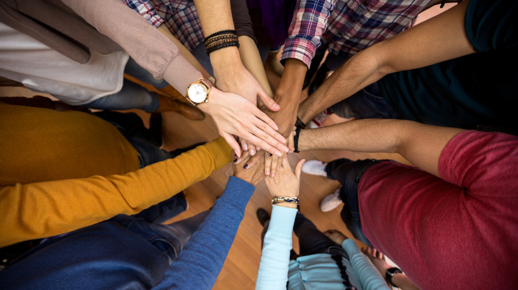 Eight hands all together in the middle to represent a team