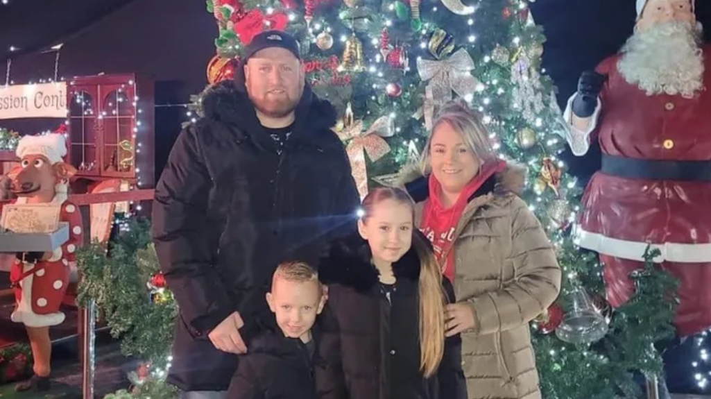 A young family stood in front of Christmas decorations