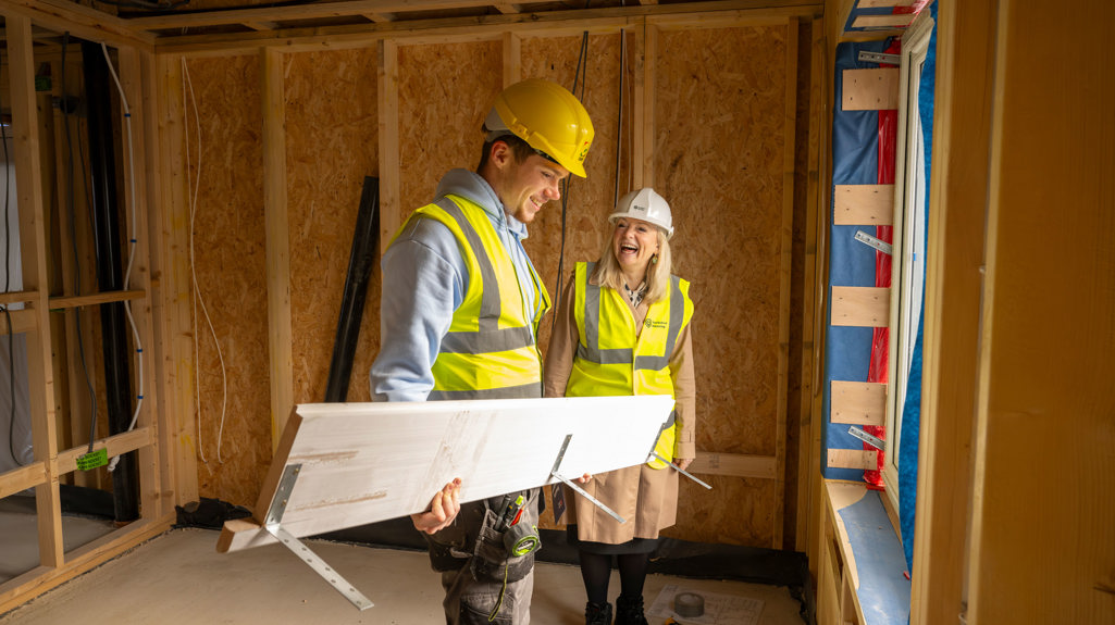 Tracy Brabin with an apprentice, both are wearing hi vis and hard hats on site
