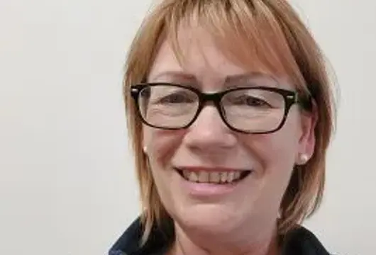 A picture of Tracey Tucker smiling at the camera wearing a blue fleece top. 