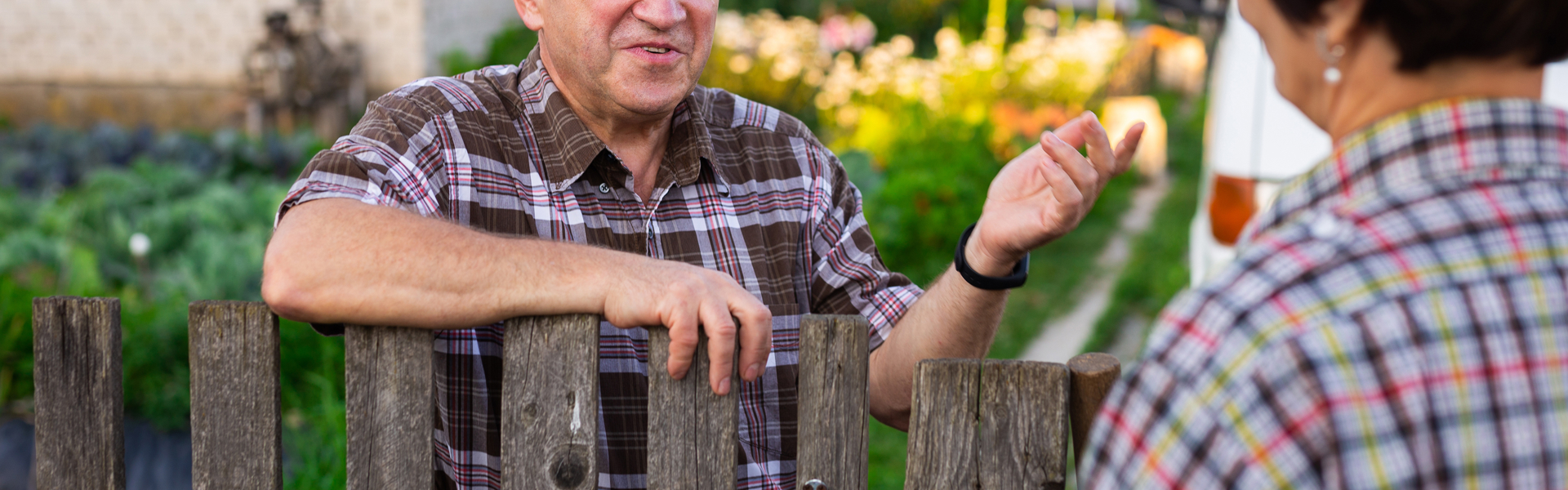 Picture of an older man speaking to someone over a garden fence