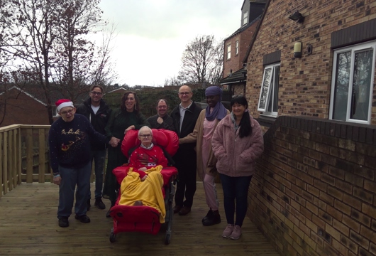 Group of people on outside decking area looking at camera and smiling