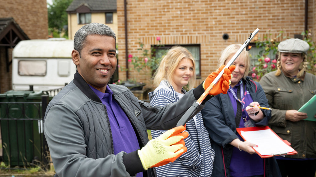 Four colleagues smiling out and about in Keighley, there's a man closest to the camera holding a litter picker and smiling at the camera 