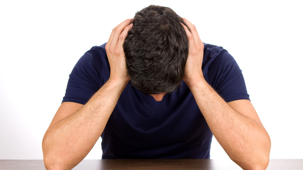 A man sat at his desk with his head in his hands. 