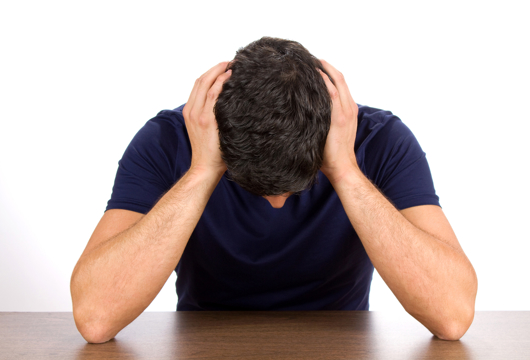 A man sat at his desk with his head in his hands. 